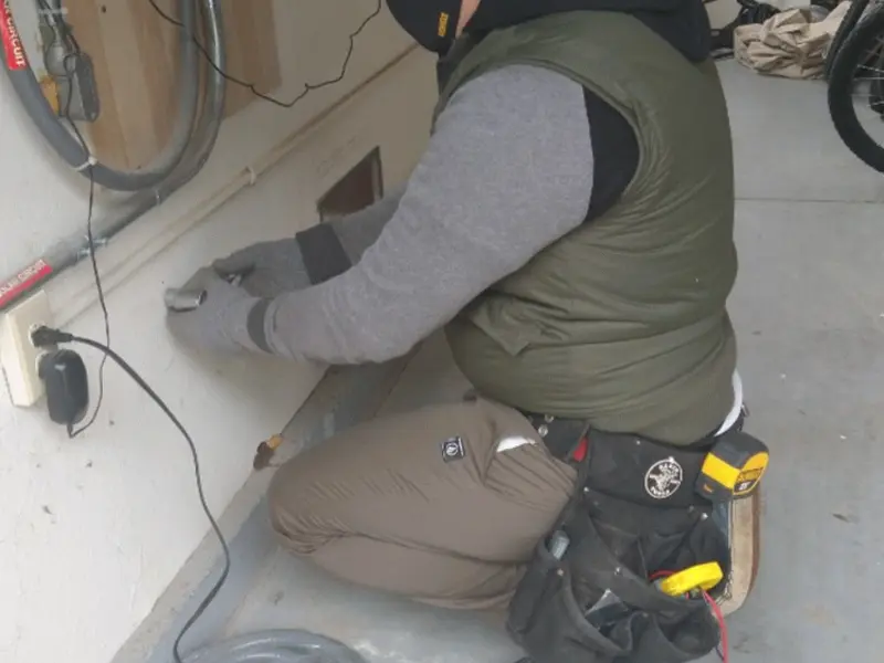 Electrician performing outlet wiring in a Triangle garage